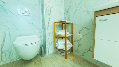 a bathroom with a toilet and a shelf with towels at ART Hotel Tirana in Tirana