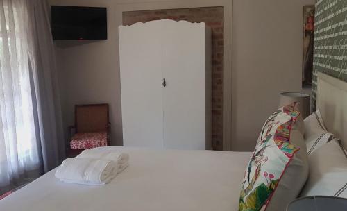 a bedroom with a white bed with towels on it at Dancing River Guesthouse in Vereeniging