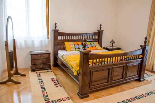 Un dormitorio con una gran cama de madera con sábanas amarillas. en Villa Ramonte en Cetinje