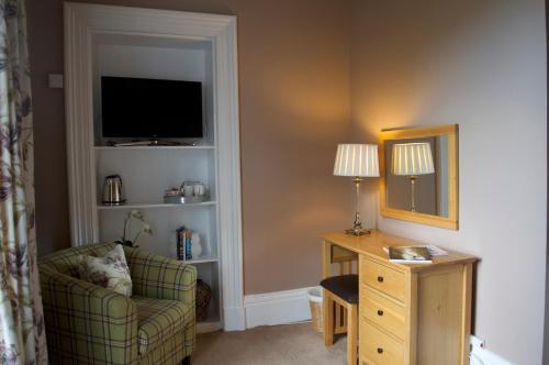 Cette chambre comprend une chaise, un bureau et une télévision. dans l'établissement Balnearn House, à Aberfeldy
