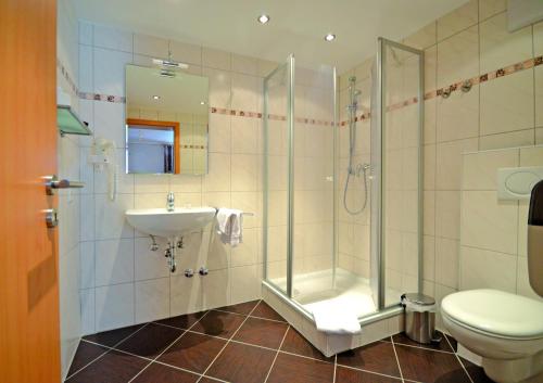 a bathroom with a shower and a sink and a toilet at Hotel Gästehaus auf der Lay in Beilstein