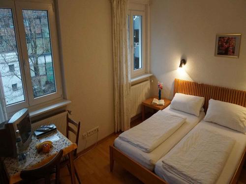 a bedroom with two beds and a desk with a tv at Hotel-Pension Goldene Krone in Freiburg im Breisgau