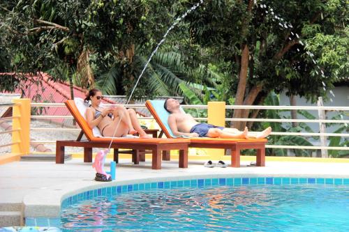 two people sitting in chairs next to a swimming pool at Coco Palm Hotel Koh tao in Koh Tao