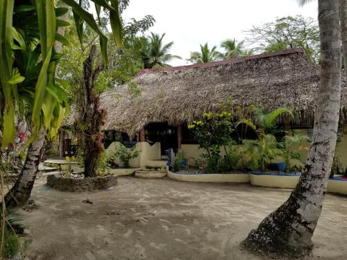 a house with a thatched roof with trees and plants at Playa Paraiso en Magante in La Yagua