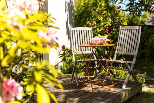 dwa krzesła i stół z kwiatami na ganku w obiekcie Studio Les Terrasses de Kerangall w mieście Brest