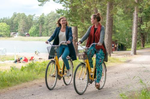 two women riding bikes on a path near a lake at Hasselö Hostel in Hasselö