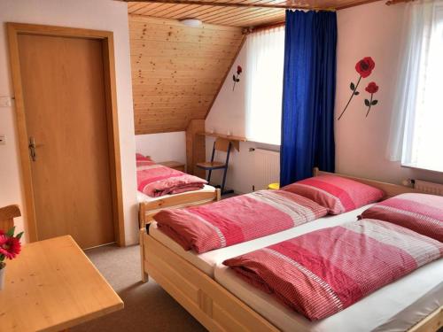 a bedroom with two beds with red sheets and a table at Stöckmann in Neuenkirchen