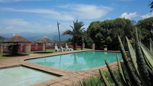 a swimming pool in a resort with mountains in the background at Jock-Sabie Lodge in Sabie
