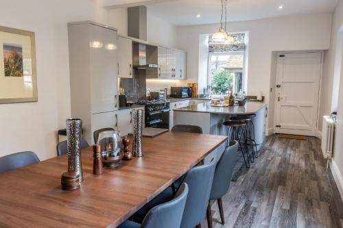 a kitchen with a long wooden table and blue chairs at The Firs in Bowness-on-Windermere