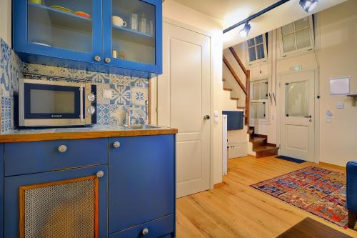 a kitchen with blue cabinets and a microwave at Hotel Antique in Ioannina