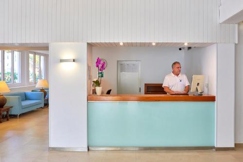a man is standing at a counter in a room at Gavimar Cala Gran Hotel and Apartments in Cala d´Or