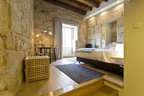a bedroom with a bed and a stone wall at RVA - Sao Joao Novo Apartments in Porto
