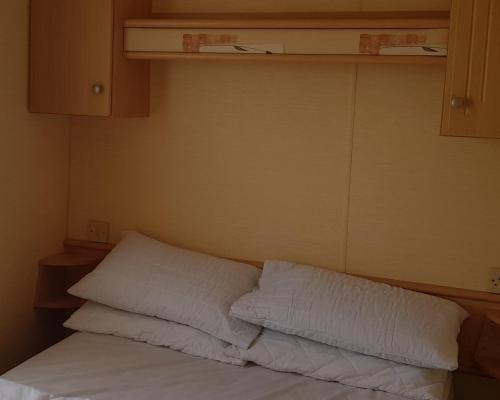 a bed with white sheets and pillows in a room at 4 Berth with private Garden - 58 Brightholme Holiday Park Brean! in Brean