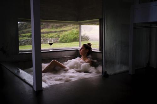a woman sitting in a bath tub with a glass of wine at Pico da Vigia in Santa Bárbara