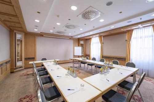 a conference room with long tables and chairs at Atomis Hotel Munich Airport by Mercure in Oberding