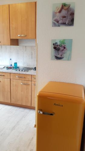 an orange refrigerator in a kitchen with wooden cabinets at Ferien-& Monteurwohnung Koenen2 nah am Westfield Centro in Oberhausen