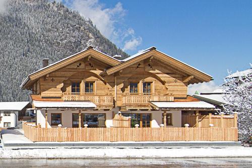 a large wooden house with a snow covered mountain at Alpenchalet Brücke in Mayrhofen