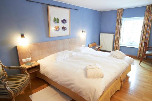 sypialnia z dużym białym łóżkiem i krzesłem w obiekcie Manoir Kasselslay w mieście Clervaux