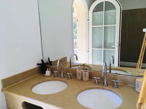 a bathroom with two sinks and a large mirror at Le Clos des Sept Palmiers in Cavalaire-sur-Mer