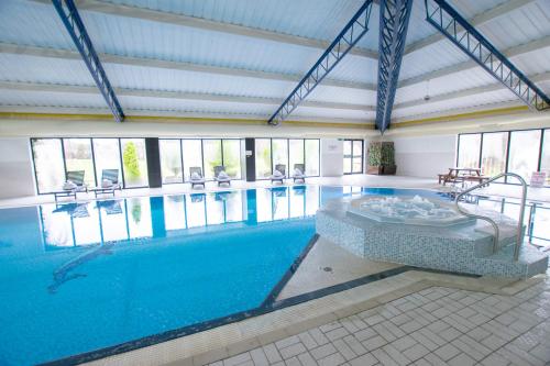 a large swimming pool with a tub in a building at Muthu Glasgow River Hotel in Erskine