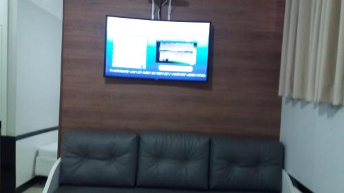 ein Wohnzimmer mit einem Sofa und einem Flachbild-TV in der Unterkunft Hotel Real in Teófilo Otoni