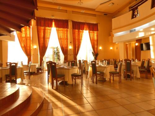 uma sala de jantar com mesas, cadeiras e janelas em Eurohotel em Baia Mare