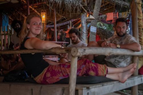 a woman laying on a table with two men at Backpack Beach Hostel & Reggae Bar in Galle