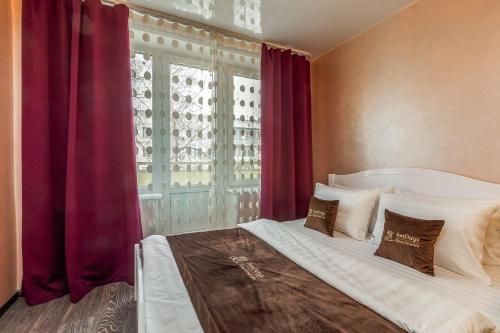 モスクワにあるInnDays on Belyaevo 110のベッドルーム1室(ベッド1台付)、赤いカーテン付きの窓が備わります。