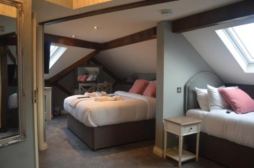 two beds in a attic room with two windows at The Royal Oak in Woodford