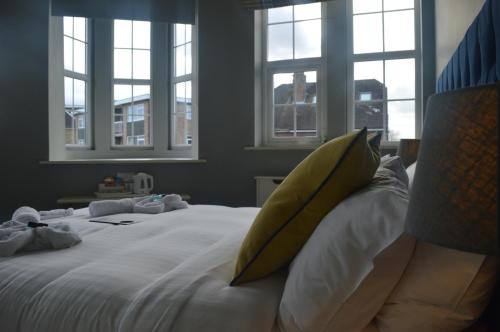 a bedroom with a bed with yellow pillows and windows at The Royal Oak in Woodford