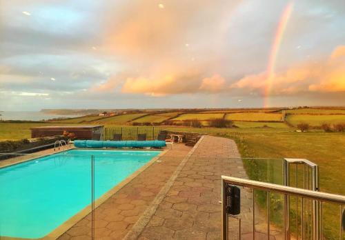 a large swimming pool with a rainbow in the background at The Pickwick Inn & Oliver's Restaurant in Padstow