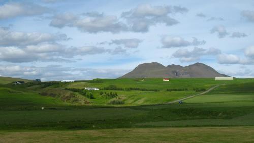 a green field with a mountain in the background at Guesthouse Húsid in Hlíðarendi