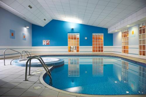 a large swimming pool in a building with blue walls at Milton Hill House in Didcot