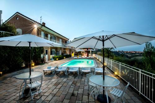 eine Terrasse mit Tischen und Sonnenschirmen neben einem Pool in der Unterkunft Holiday Residence Belohorizonte in Macerata