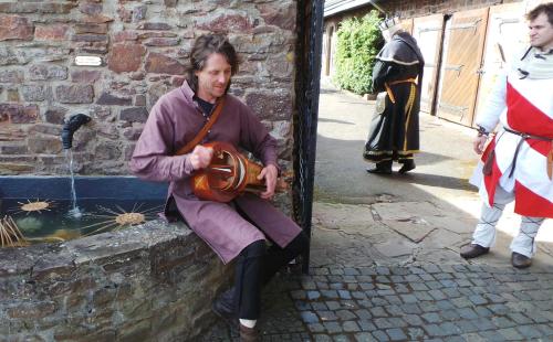 a man sitting on the side of a building holding a drum at Hotel Burg Arras in Alf