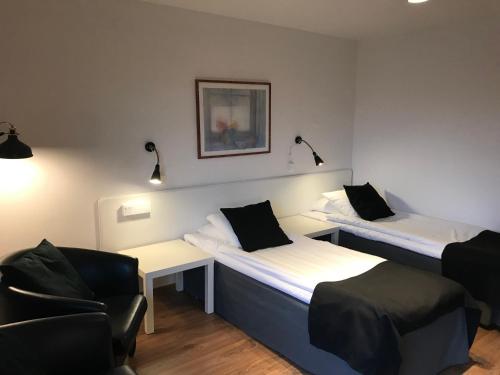 a room with two beds and a chair at Hotel Småland in Skillingaryd