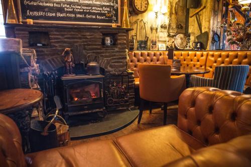 a bar with a fireplace and a couch and a table at The Pickwick Inn & Oliver's Restaurant in Padstow