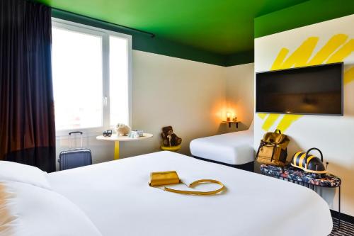a hotel room with a bed and a tv at ibis Styles Lyon Meyzieu Arena Stadium in Meyzieu