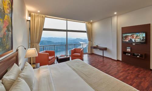 a hotel room with a bed and a flat screen tv at Ragamaya Resort & Spa Munnar in Munnar