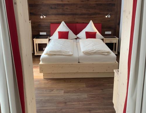 a bedroom with a bed with red and white pillows at Hotel Restaurant Neu Meran in Bad Reichenhall