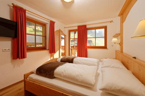 a bedroom with two beds with red curtains and a tv at Waldlechn in Cadipietra