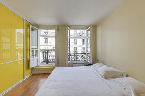 a large bed in a room with two windows at ID 308 Châtelet Rivoli in Paris
