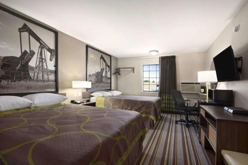 a hotel room with two beds and a flat screen tv at Super 8 by Wyndham Ardmore in Ardmore