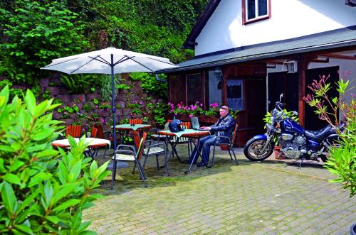 a woman sitting at a table with an umbrella at Hotel Gästehaus auf der Lay in Beilstein