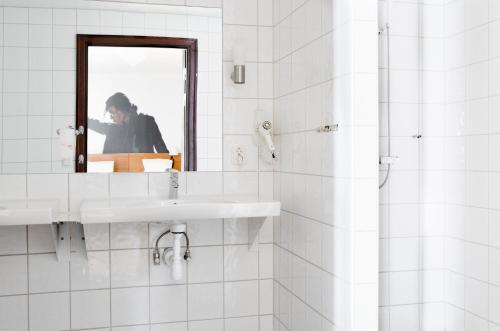 La salle de bains blanche est pourvue d'un lavabo et d'un miroir. dans l'établissement Comfort Hotel Eskilstuna, à Eskilstuna