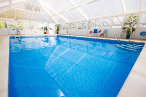 a large swimming pool with blue water in a building at The Lakes Rookley in Rookley