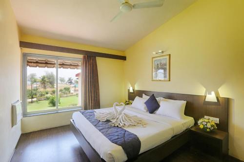 1 dormitorio con 1 cama grande y ventana en The Byke Old Anchor Beach Resort & Spa, en Cavelossim