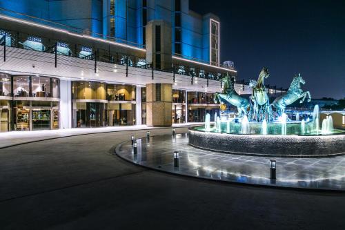 een fontein voor een gebouw 's nachts bij Babylon Rotana Hotel in Bagdad