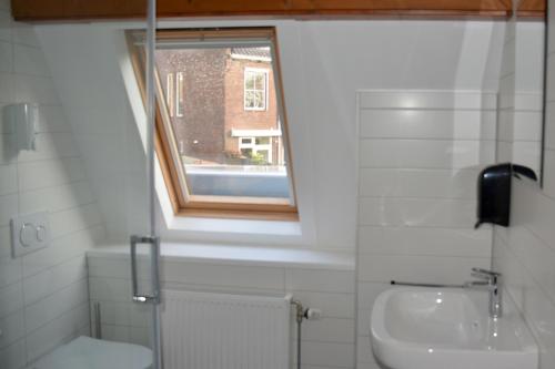 baño con aseo y lavabo y ventana en Short Stay Wageningen, en Wageningen