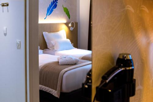 a hotel room with a bed and a mirror at Kyriad Prestige Amiens Poulainville - Hotel and Spa in Poulainville